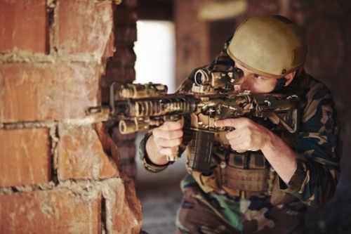 Dr. Michael Dadson counsels military veterans with challenges such as PTSD Soldier passing brick wall, weapon ready - Michal Dadson Counsels Veterans for PTSD and more